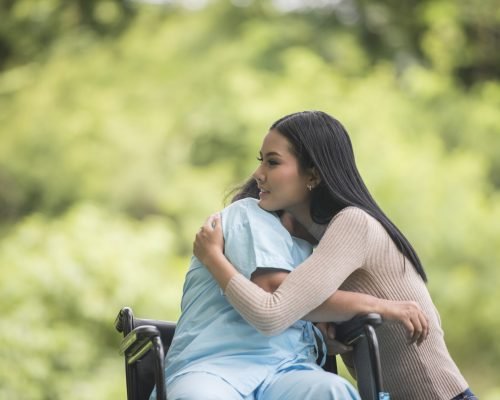 Granddaughter talking with her grandmother sitting on wheelchair, cheerful concept, happy family